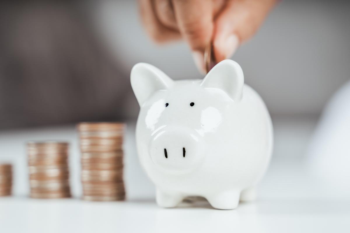 Main insérant une pièce de monnaie dans une tirelire cochon