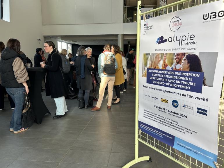 Affiche atypie friendly devant un groupe de personnes prenant un café 